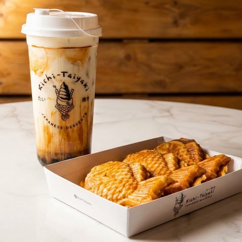 A Kichi-Taiyaki bubble tea and a box of taiyaki pastries on a marble table.