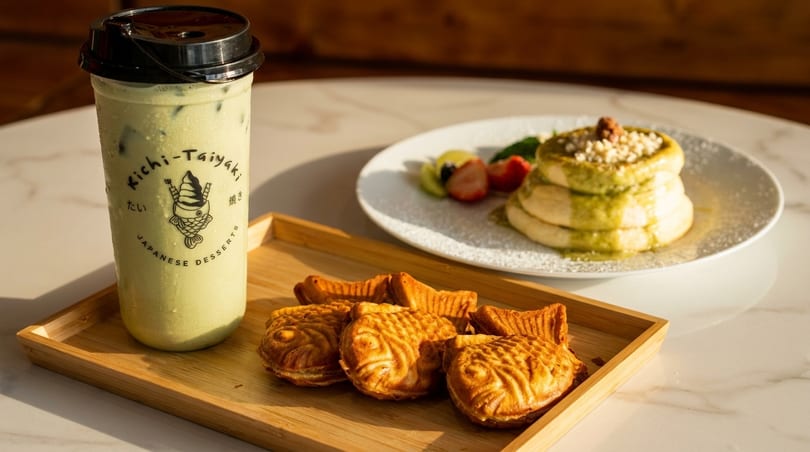 Matcha boba, taiyaki, and matcha pancakes with fruit on a white marble table.